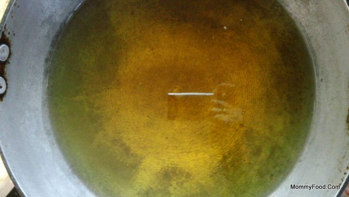 Heating oil in a vessel for frying Kaaram Poosa